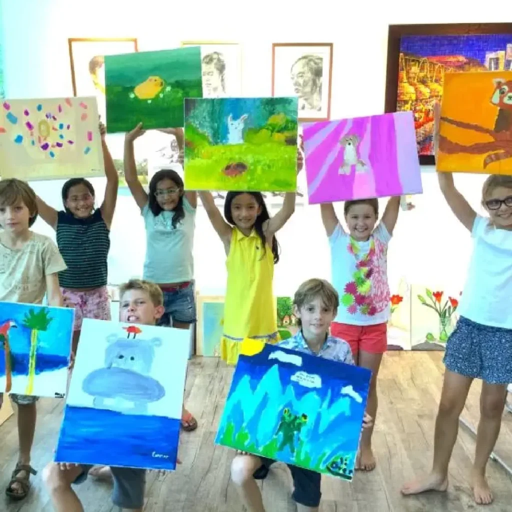 아이들이 야외 같은 스튜디오에서 아크릴, 오일 파스텔, 마커로 그림을 그리고 중국 서예를 배우는 모습