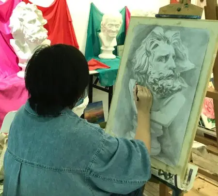 Student doing observational plaster cast drawing and sketching artwork