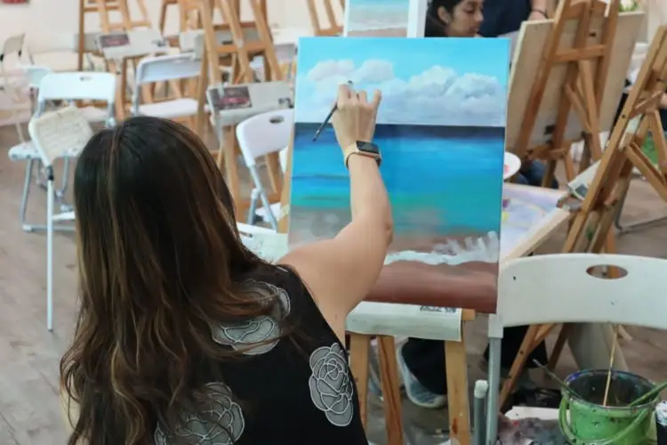Our student working on her acrylic painting of a landscape.