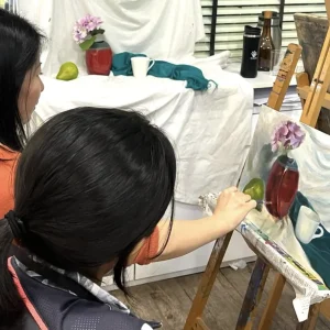 Student wearing a mask painting an acrylic artwork in a studio setting