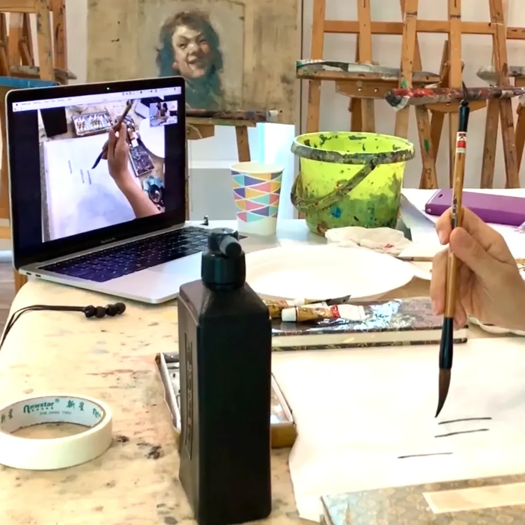 Student practicing traditional Chinese ink painting during a Zoom live session