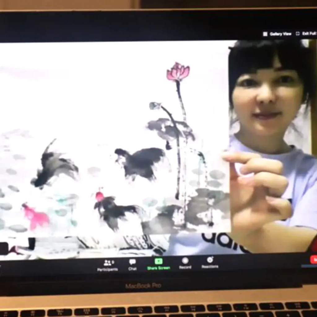 Participant painting a traditional Chinese fan with ink during a Zoom live art session
